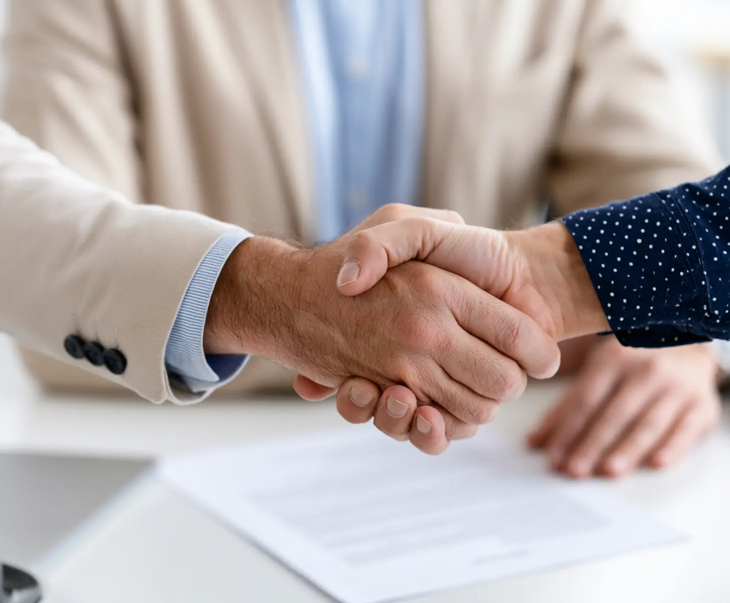 Handshake over a signed document at a desk