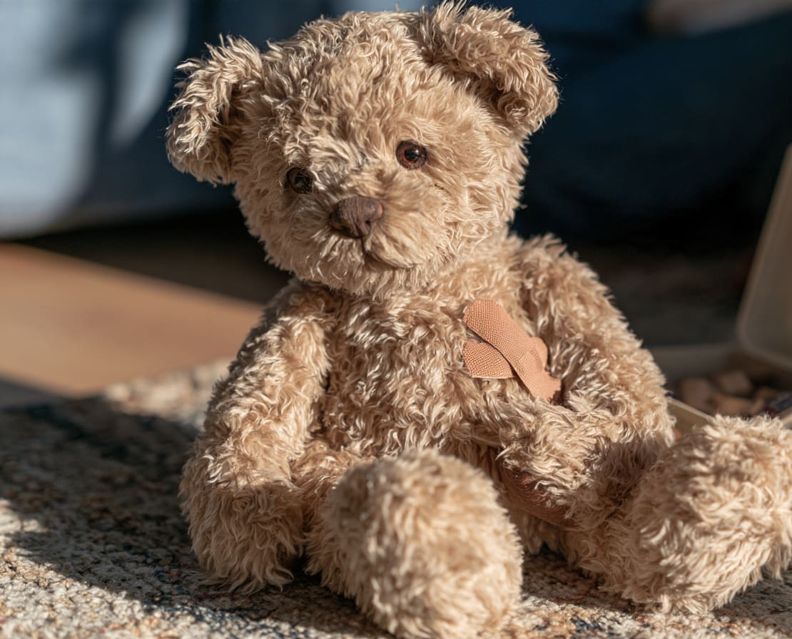 Orsacchiotto con un cerotto sul tappeto della cameretta: il primo soccorso ai bambini piccoli nel corso di babysitter