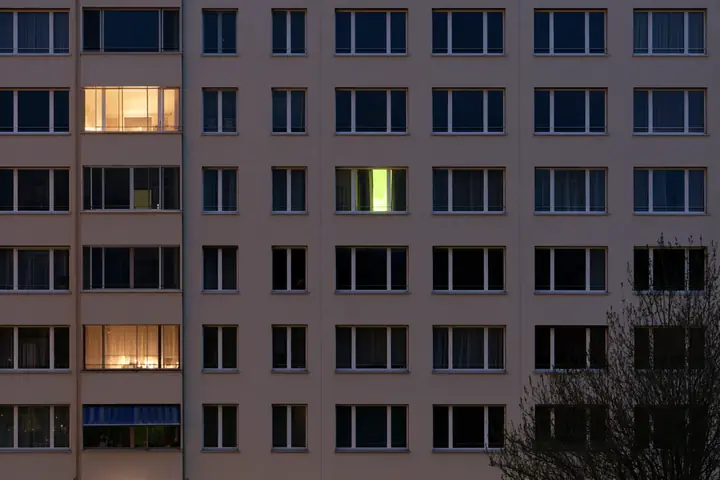 Facciata di un condominio svizzero al crepuscolo, alcune finestre illuminate